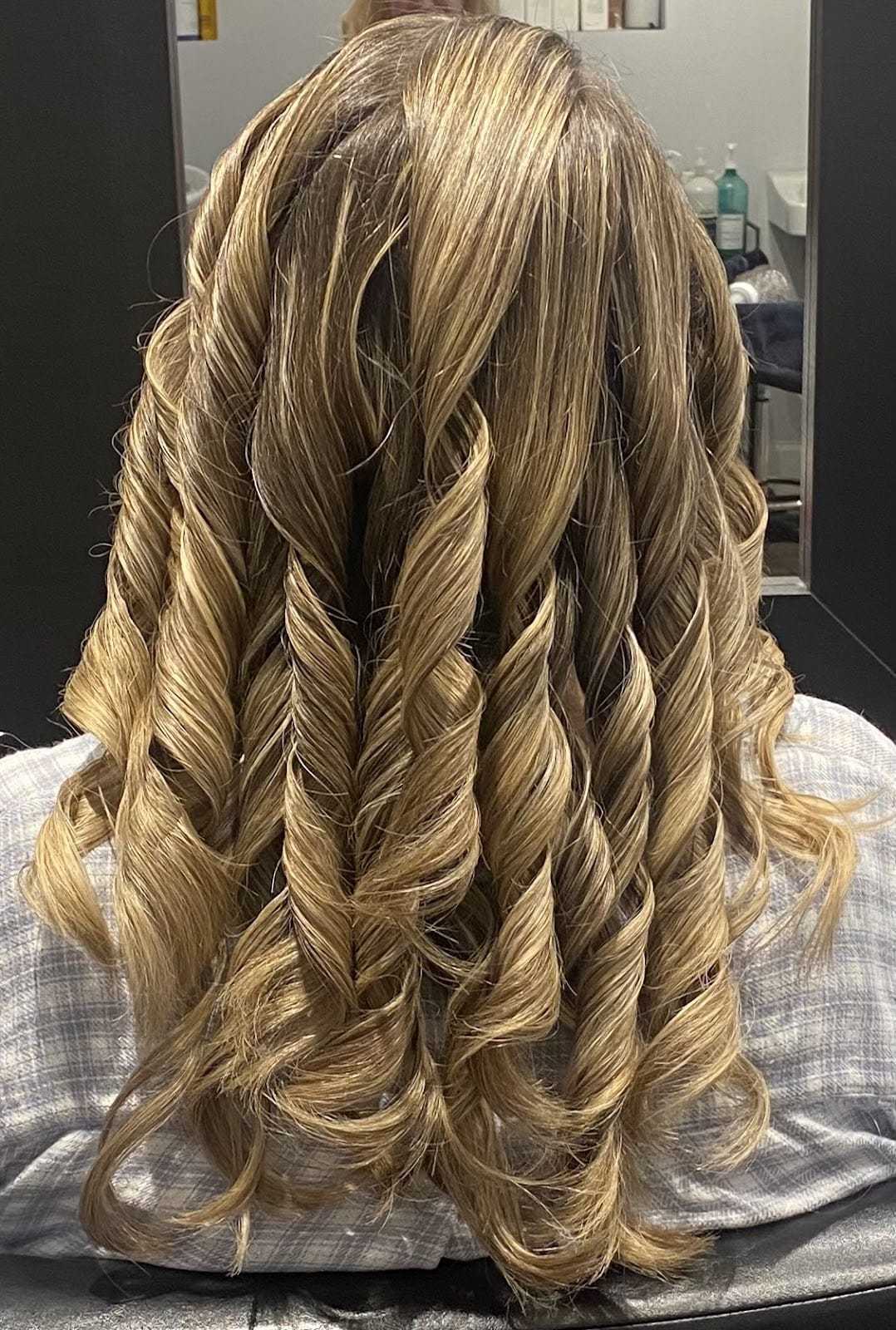 Curled hair with blonde highlights styled in defined ringlets from the back view.