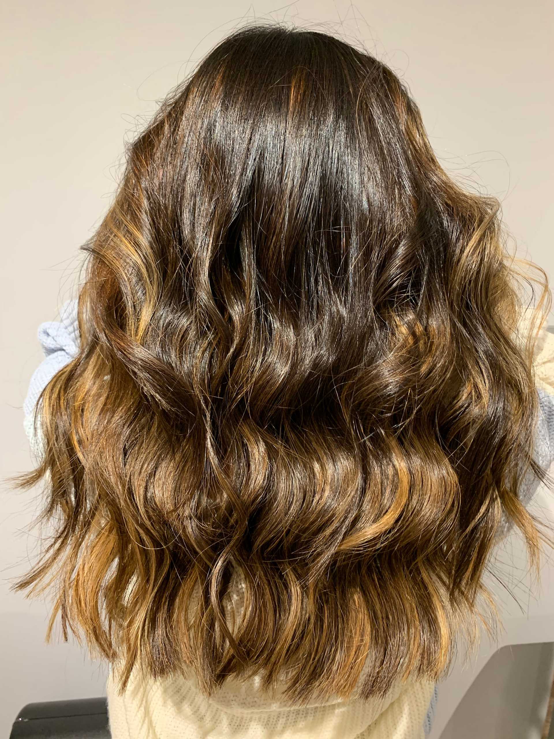 Wavy brown hair with natural highlights on a person, shown from the back.